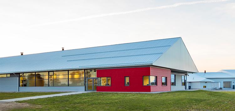 Red barn surrounded by green grass and blue sky.