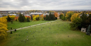 View of Johnston Green from top of Johnston Hall, various trees surrounding background as students walk across Johnston Green