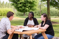 Three students studying at a picnic table