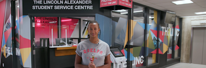 Student standing in front of doors to the Lincoln Alexander Student Service Centre