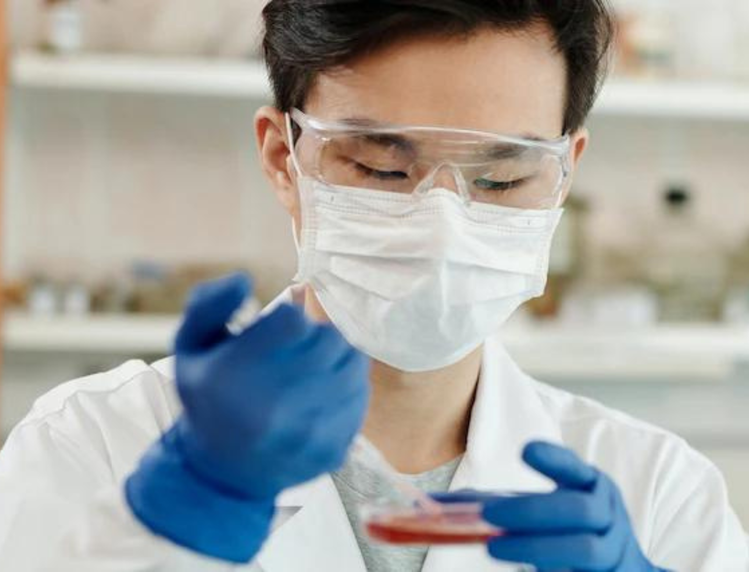 Biomedical Toxicology student wearing lab gear analyzing a liquid.