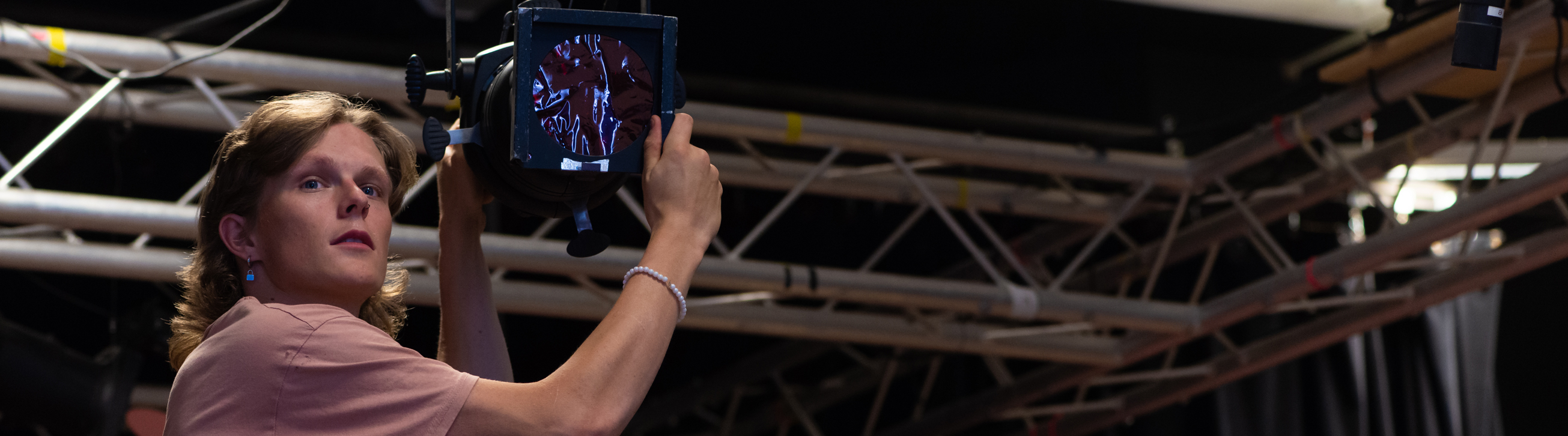 Ryan Ahlers adjusting a spotlight in a theatre