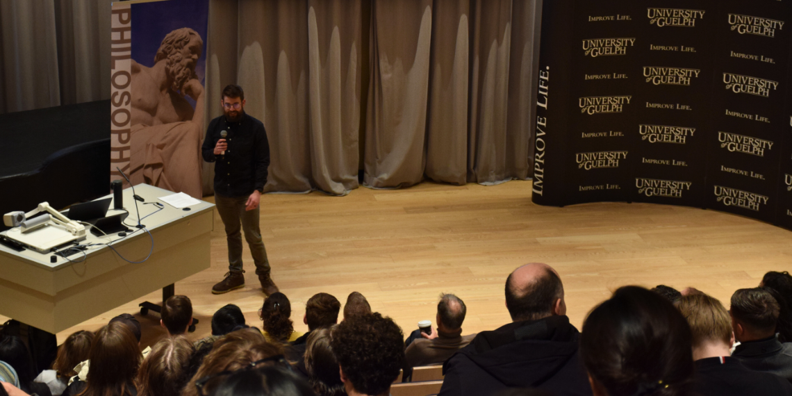 Dr. Gus Skorburg, associate professor of Philosophy and academic co-director of the Centre for Advancing Responsible and Ethical Artificial Intelligence, speaks to attendees at the Second Annual Guelph Regional High School Ethics Bowl in the auditorium in the College of Arts in the MacKinnon Building at the University of Guelph on February 8, 2025.