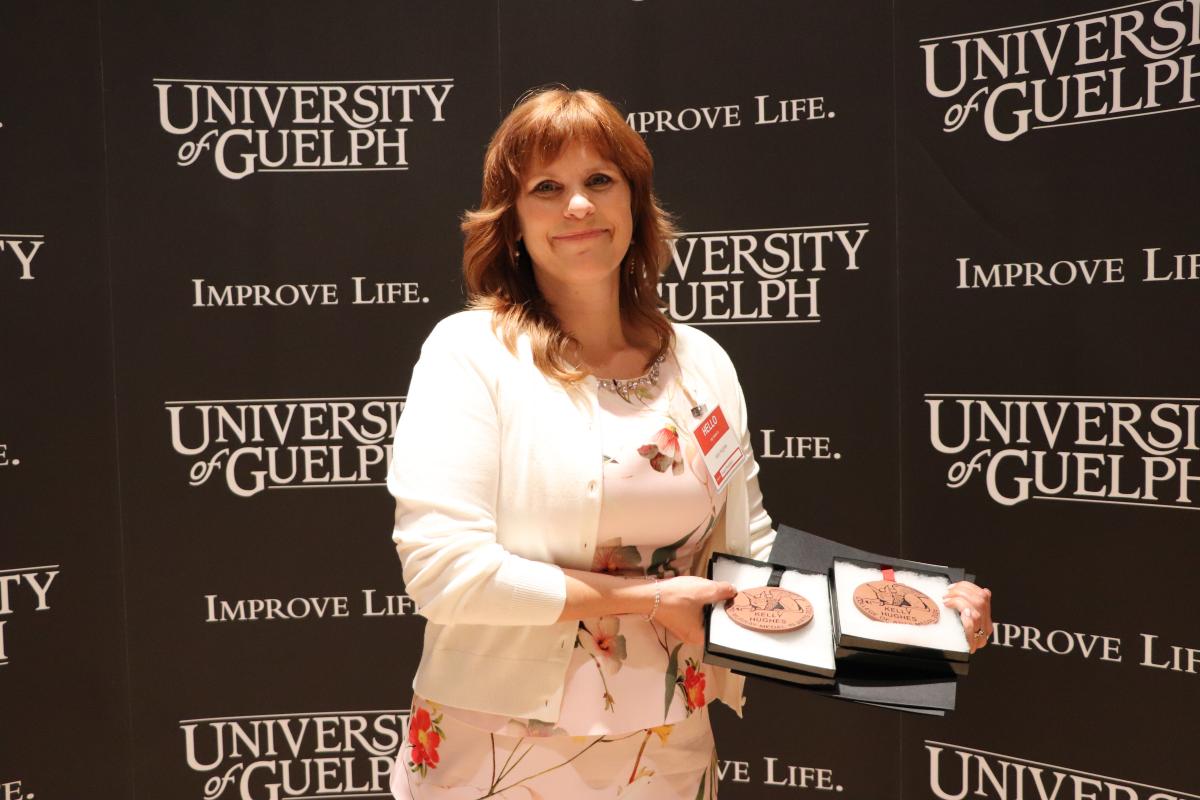 Kelly Hughes at the Award Convocation, holding her awards and medals