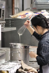 Elaine using a double boiler in the galley to prepare fudge.