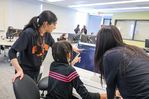 Two Go CODE Girl volunteers helping a student.