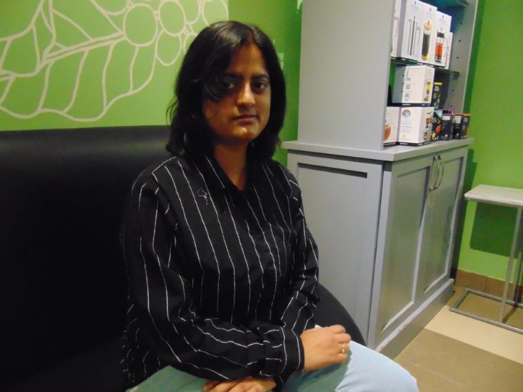 Keerthana Madhaven sits and looks at the camera inside with a green painted background