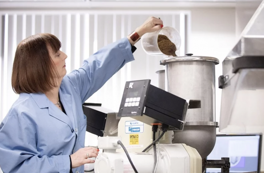 Image of woman pouring coffee beans into machine