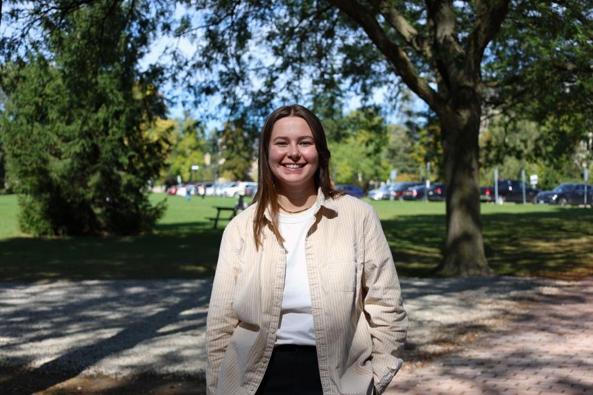 Aeryn Mac Isaac standing on Alumni Walk in front of trees near Johnston Green.