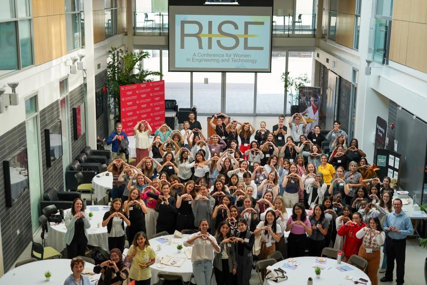 Large group of RISE attendees, speakers, and event organizers gathered, standing, in the Adams Atrium for an overhead group photo.