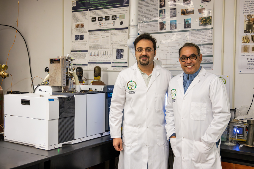 Dr. Omid Norouzi and Dr. Animesh Dutta wearing lab coats and standing next to a machine in the lab.