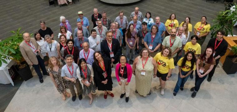 Overhead image of a large group of faculty, staff, alumni, and students who participated in the Chem 150 symposium standing and smiling at the camera.