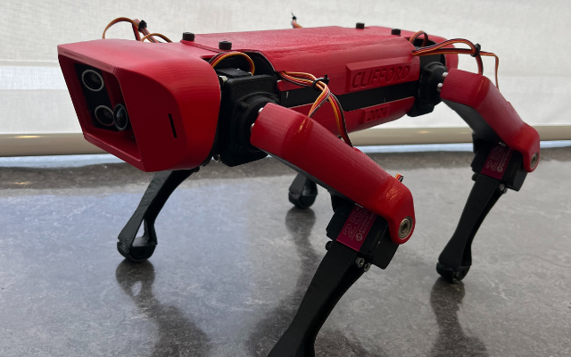 Side view of a red and black quadruped robot dog named Clifford, showcasing its sleek design and articulated limbs.