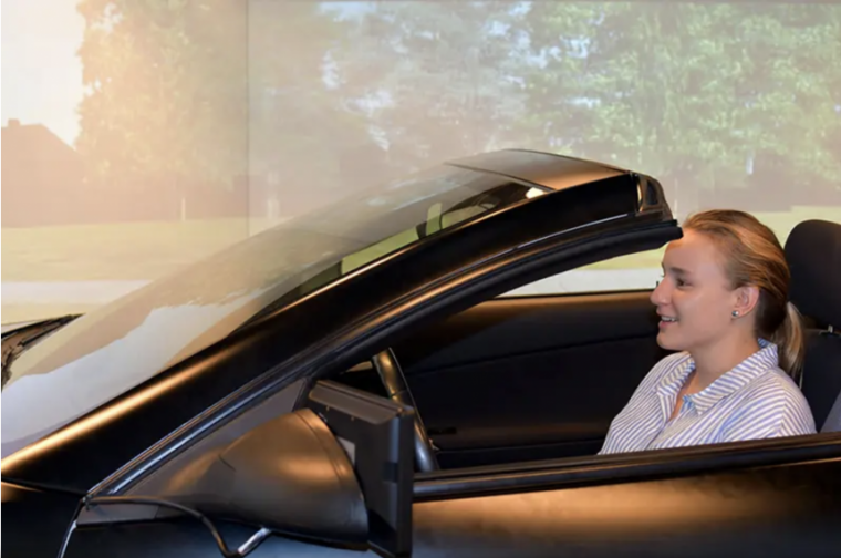 Erika Ziraldo pictured in a car with a simulated background in the DRiVE lab