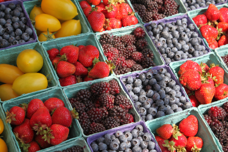 Fruits arranged at the market including lemons, blueberries, berries and strawberries.