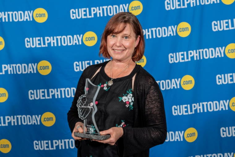 Dr. O’Meara holding award with Guelph Today background.