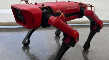 Side view of a red and black quadruped robot dog named Clifford, showcasing its sleek design and articulated limbs.