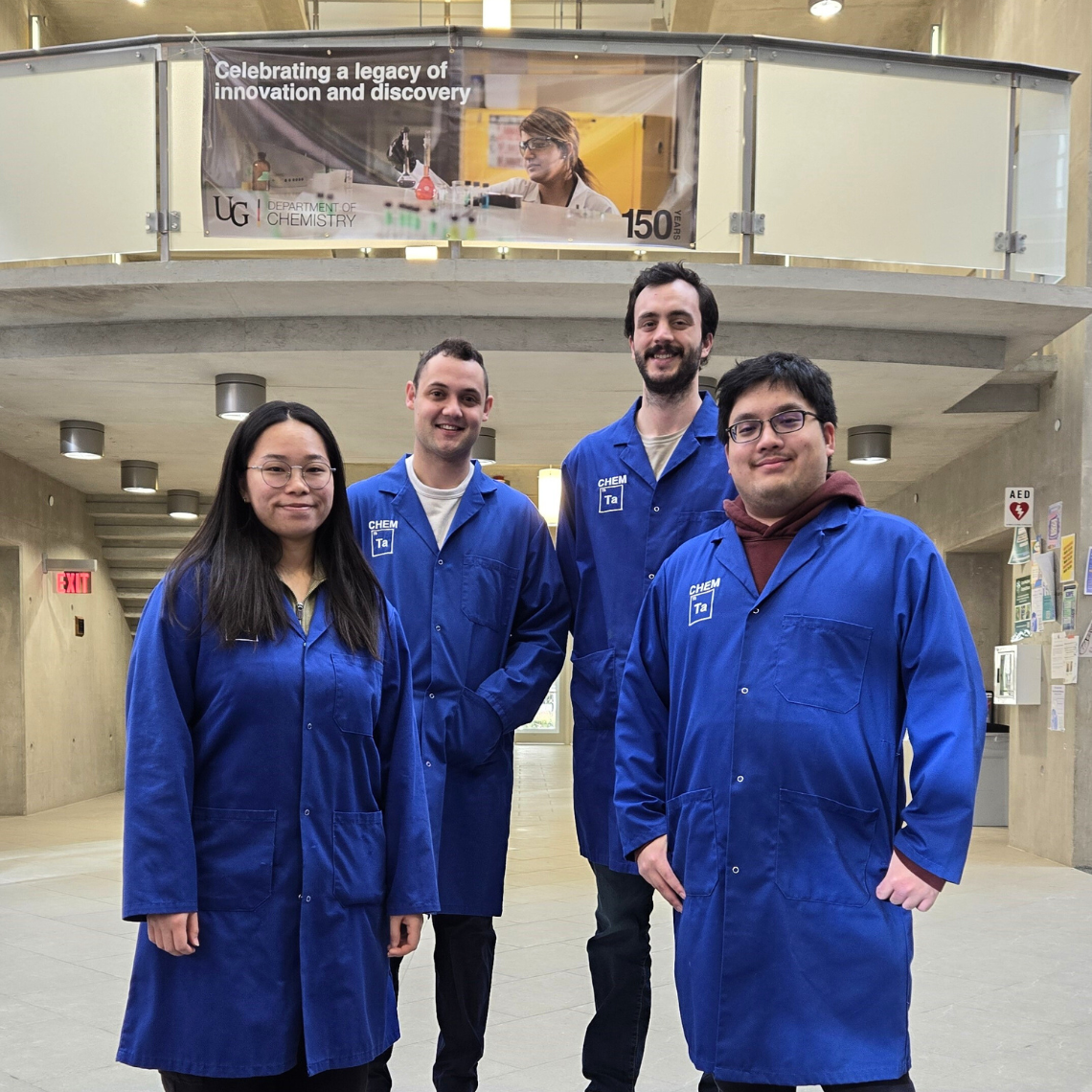  Karka Law, Keenan Regan, Joshua Van Der Zalm, and Jason Yap stand in the Waasamowin Atrium wearing blue lab coats.