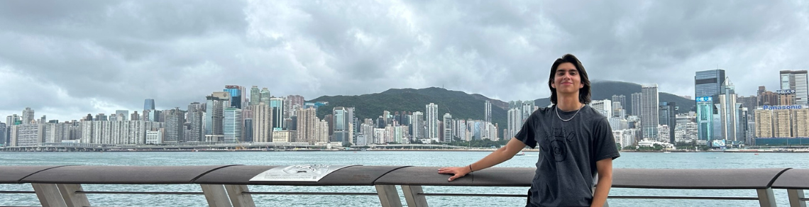 Student standing in front of the Hong Kong skyline across the river