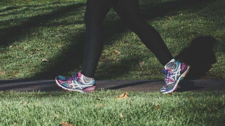 A person walking along a paved path in a park.