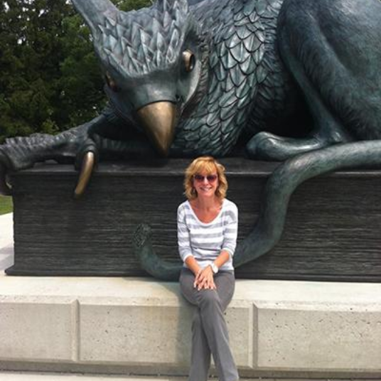Lesley Jump sitting in front of Gryph statue