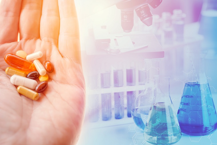 Decorative - A hand holding a variety of pills and various lab equipment in the background