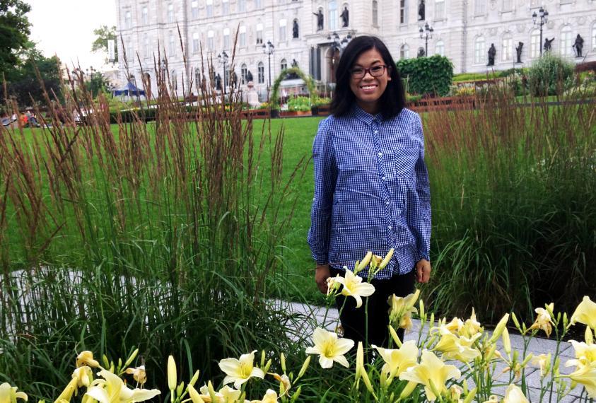 Jenny Trinh stands in a garden in front of an old building. 