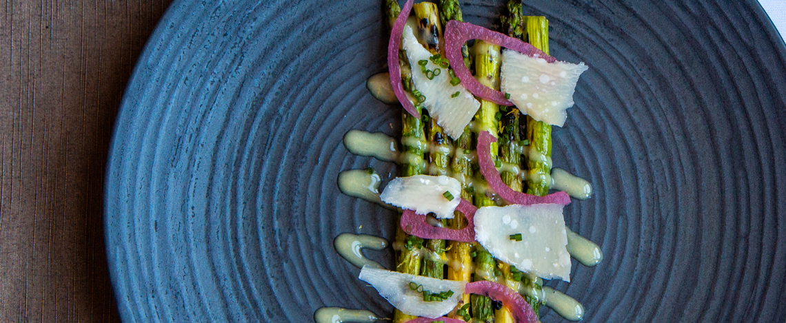asparagus salad with parmesean cheese and red onions, on a blue plate
