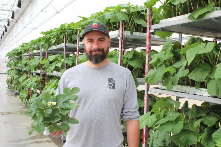 Kevin Piunno smiling for the camera while holding a plant.