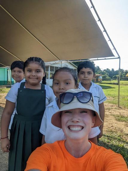 Lara-Nicole Cochrane smiling and taking a selfie with children behind her.