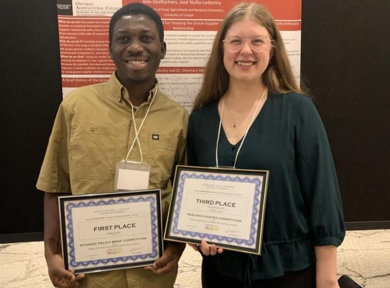 Andrews Sai and Alex DesRochers smiling while holding their competition awards.