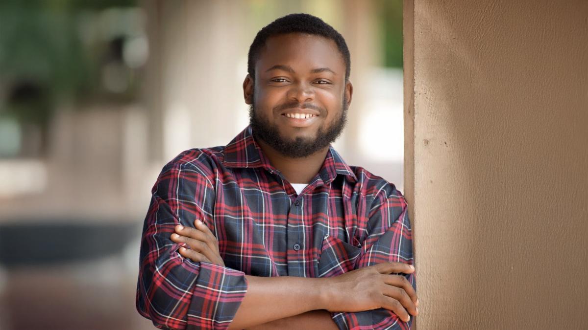 Olatunbosun Ayetan smiling at the camera confidently with his arms crossed.