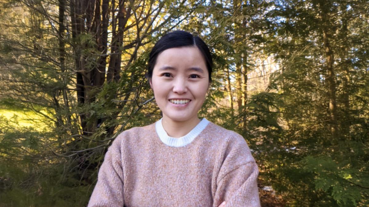 Dr. Yajun Peng smiling in a forest. 