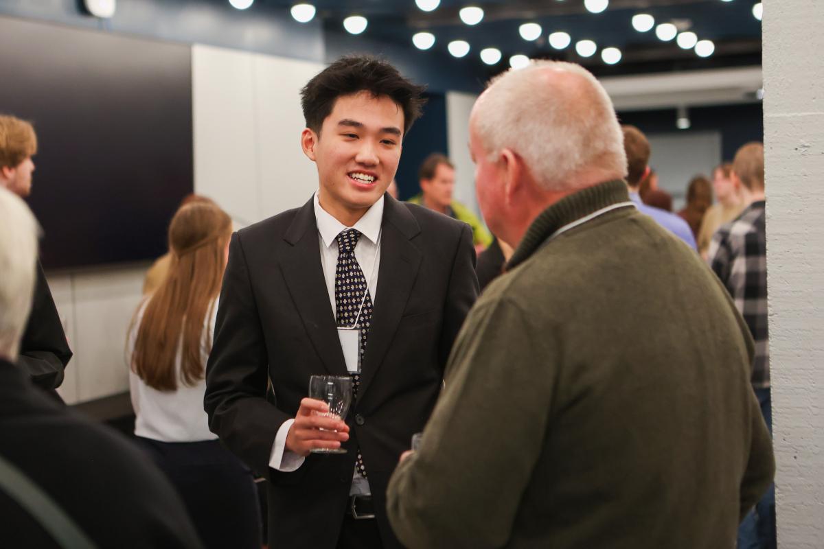 Thomas Deng smiling and speaking with someone at an awards ceremony