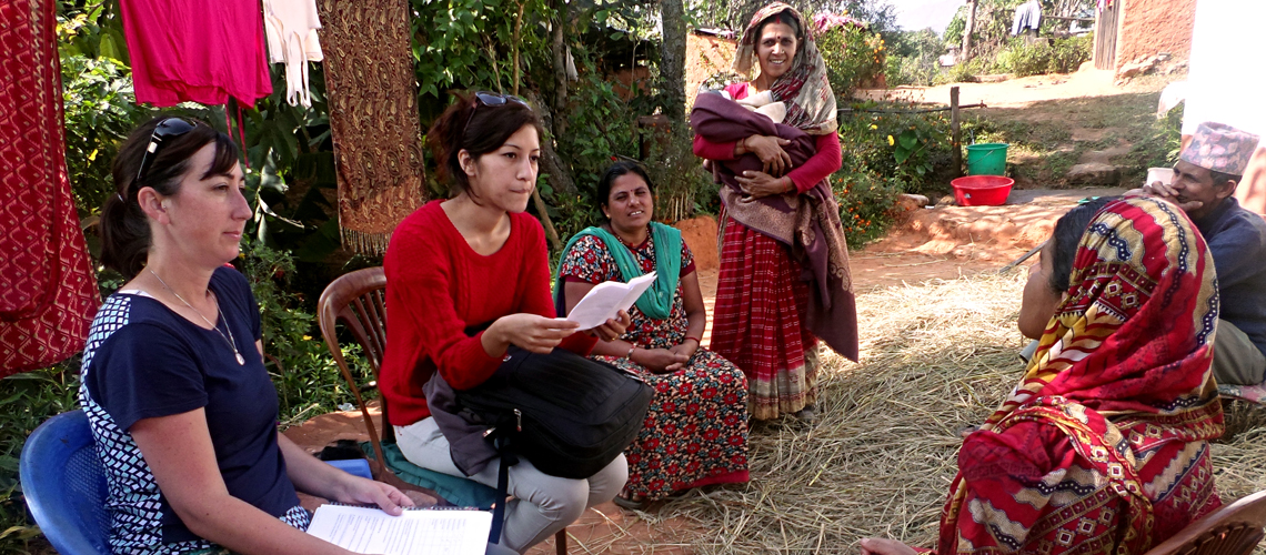 Woman and interpreter interview rural citizens outside of their home.