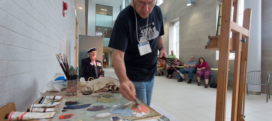 Guelph artist Greg Denton paints a portrait of former U of G president Bill Winegard for Remembrance Day project.