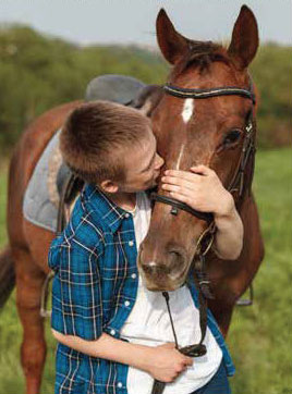 A boy kissing his horse, therapy horse research at University of Guelph.