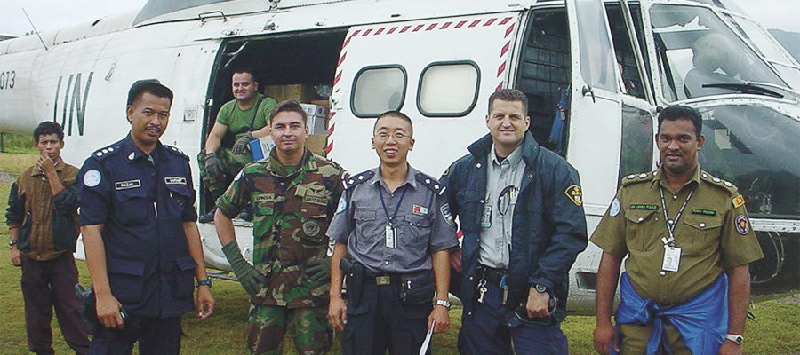 John Remillard standing in front of helicopter with other uniformed men