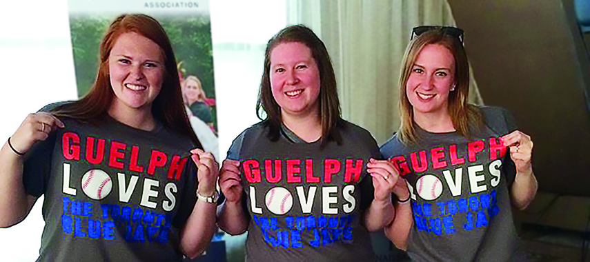 Three students at the 2017 Alumni Jays game showing off their "Guelph Loves The Toronto Blue Jays" shirts