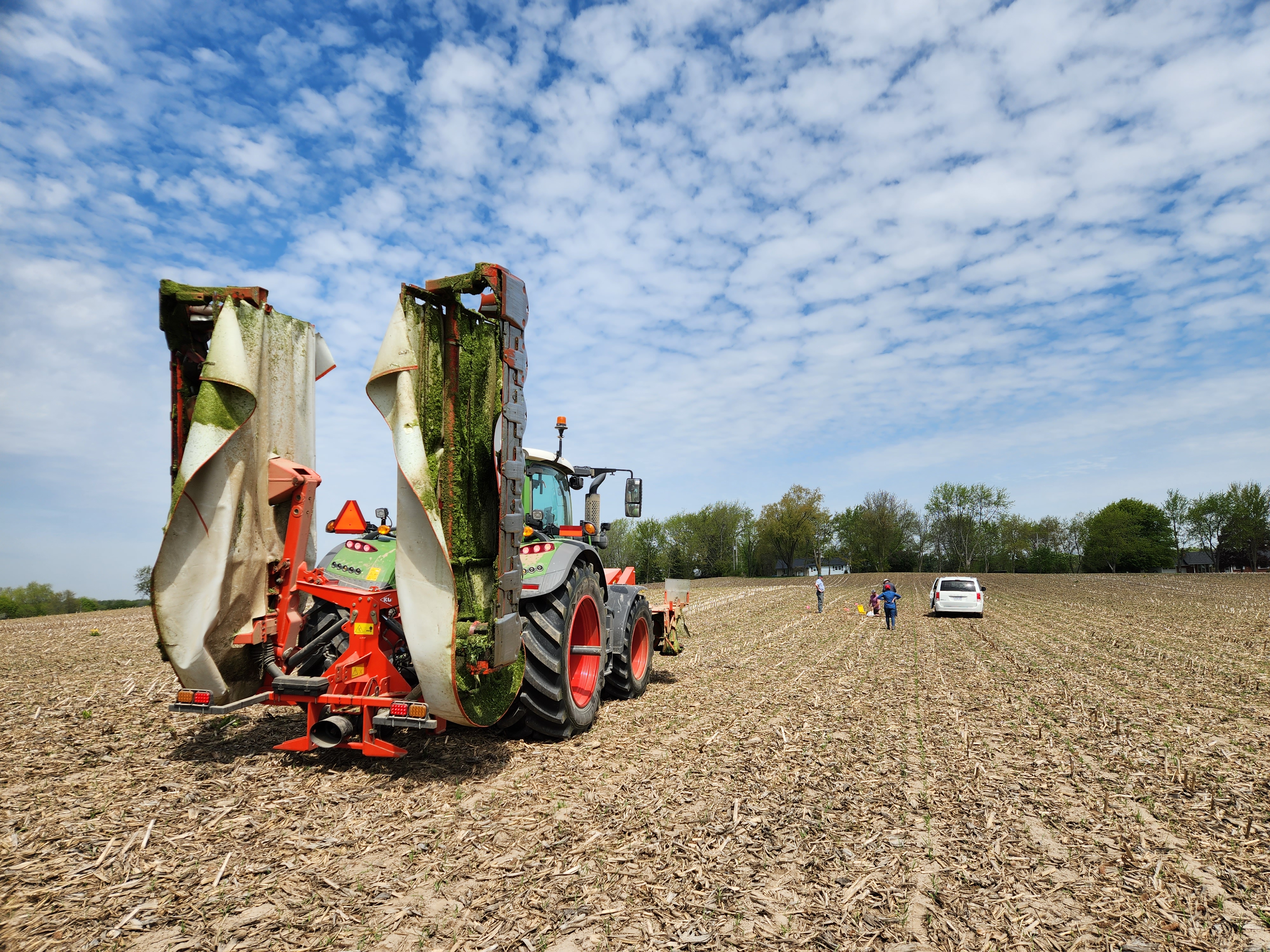 Tractor on a harvested corn field with researchers in distance preparing a research site on soil compaction.  