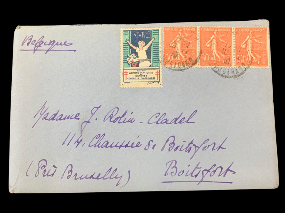 A blue envelope addressed to Madame J. Rolin-Cladel, 114 Chausée de Boitsfort, (Près Bruxelles), Boitsfort. The letter has four stamps on it; 3 of them are red and read 'République Français' and 1 is a colourful stamp featuring a child in a window with a bouquet, this stamp reads 'Vivre, Comité National de défense contre la tuberculose' (Live, National Committee for the Fight Against Tuberculosis).  