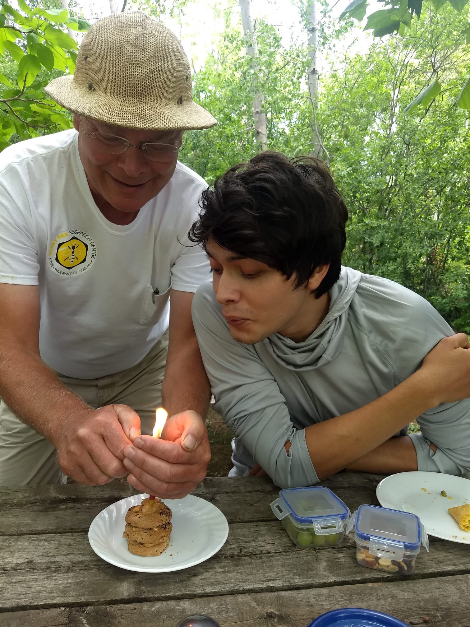 Two people who work with the Honey Bee Research Station lighting a candle