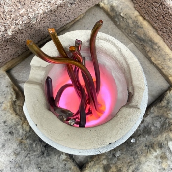 Copper reacting with the ceramic coating of a graphite crucible producing a bright pink flame.