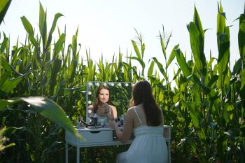 A woman sitting at a vanity in a corn field.