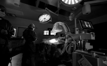 An operating room with a doctor performing surgery and another one looking on