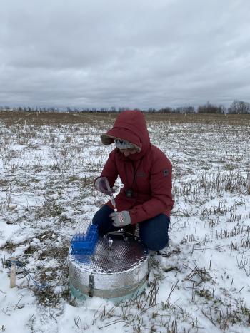 A student taking gas samples from an agricultural field.