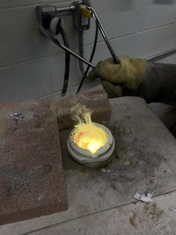 Someone melting copper and zinc c in a crucible using an induction furnace.