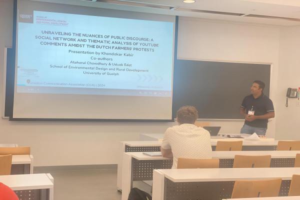 Dr. Kabir standing in front of projector displaying his presentation